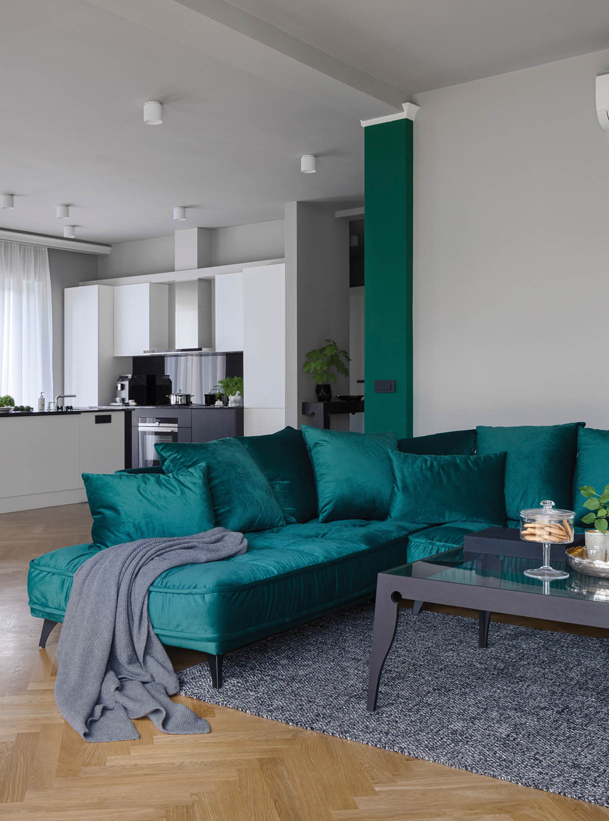 Elegant green corner sofa and modern coffee table in stylish living room with air conditioner