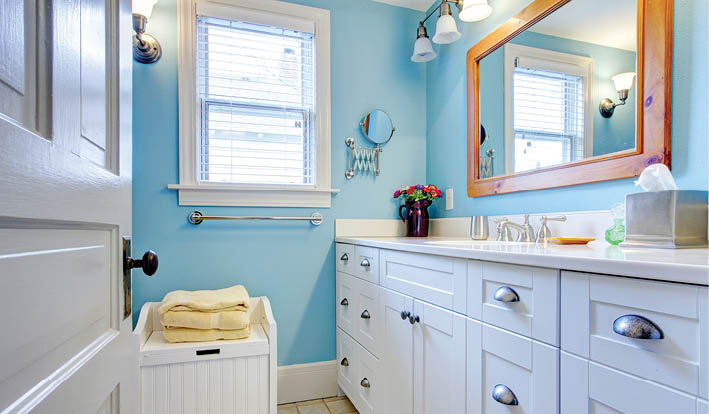 Blue and white bathroom with lots of storage space with open door 