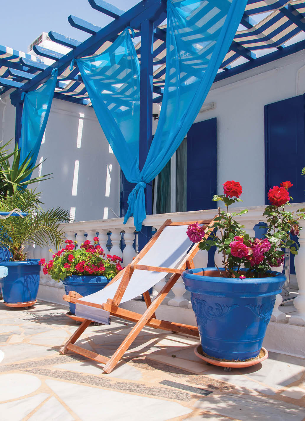 Veranda with pergola and sun beds, surrounded by flowers 