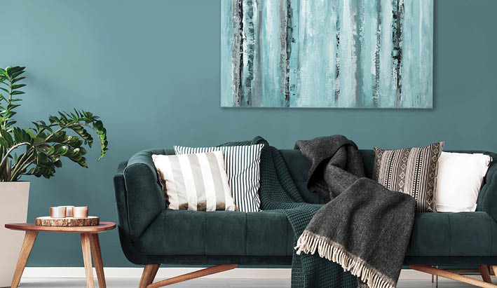 Patterned cushions on sofa next to wooden table and plant in dark apartment interior  Real photo