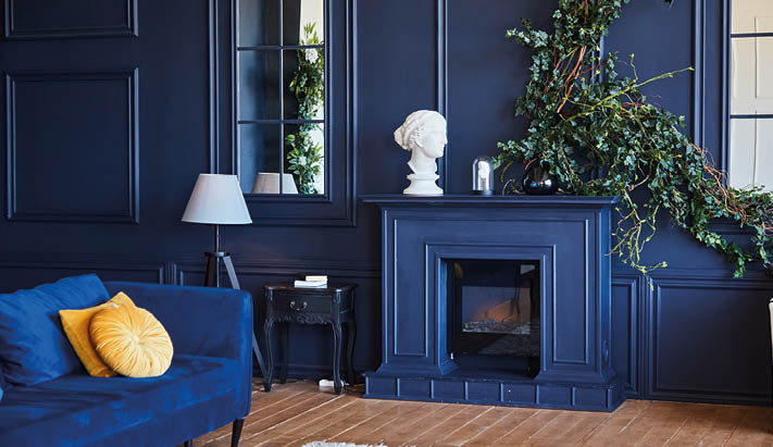 Modern interior with fireplace, spacious living room with dark blue walls and wooden floor. A real photo of the interior.