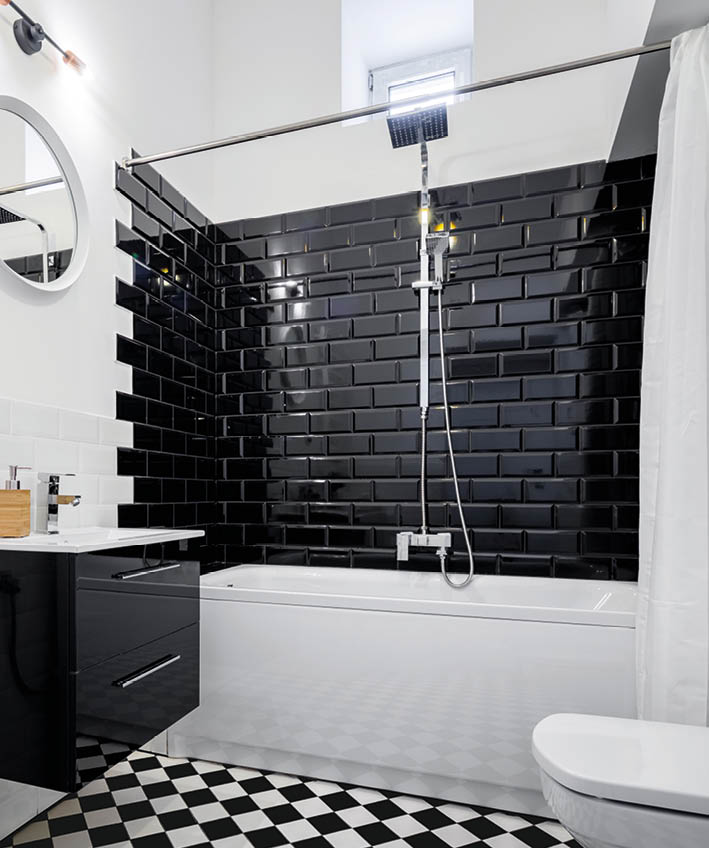 Black and white bathroom with bathtub, toilet and washer