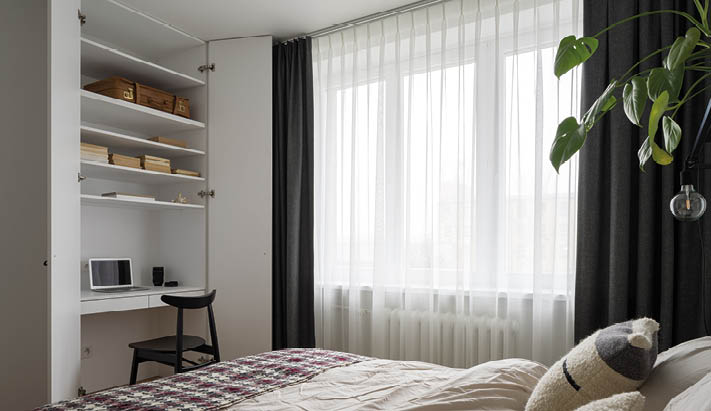 Nice bedroom with comfortable bed and big window and desk to work in white wardrobe