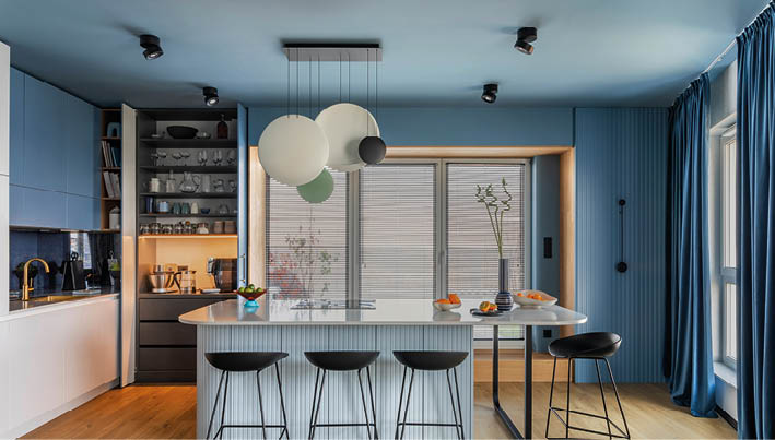 Interior design of kitchen space with marble island, black chockers, modern lamp, wooden wall, blue kitchen furnitures, vase with dried flowers and personal accessories. Home decor. Template. 