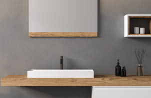 Close up of bathroom sink and a mirror. The bathroom has a modern design with a wooden countertop