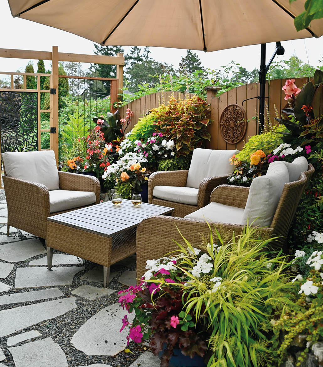 Outdoor backyard luxurious seasonal flagstone patio with cozy seating and lush tropical gardens and flowering planters