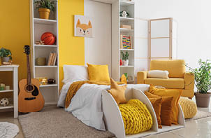 Interior of children's room with bed, shelf units and yellow armchair