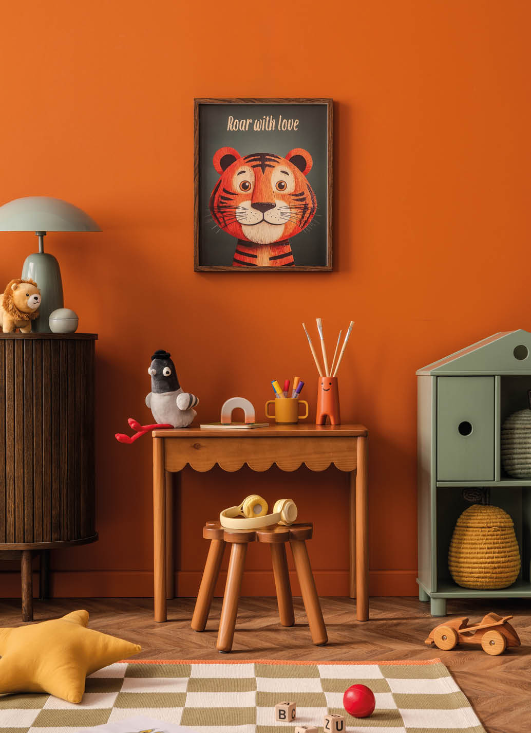 Colorful child room with wooden desk, toys and mock up poster frame. Orange vibe.