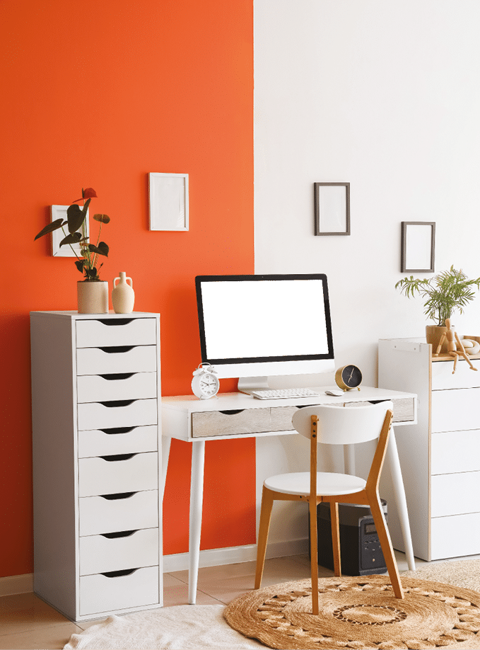 Comfortable workspace with modern computer, alarm clocks and houseplants near color wall