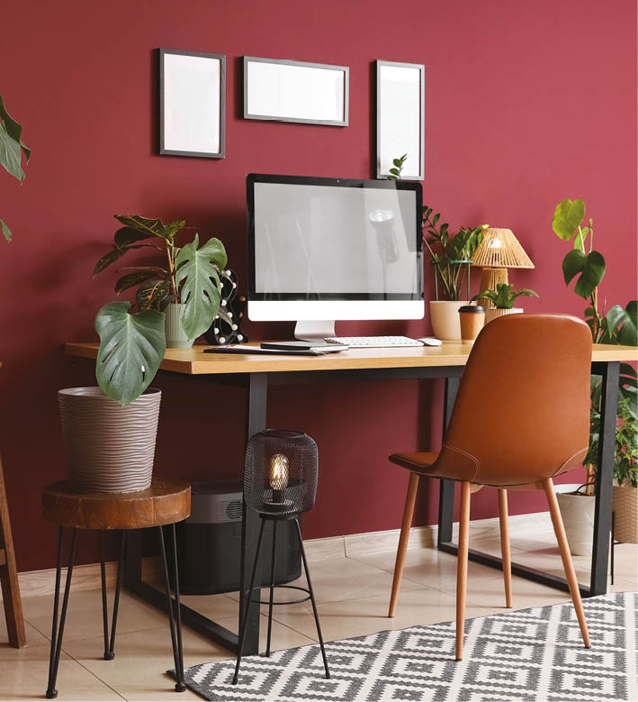 Interior of stylish office with workplace, blank frames and houseplants
