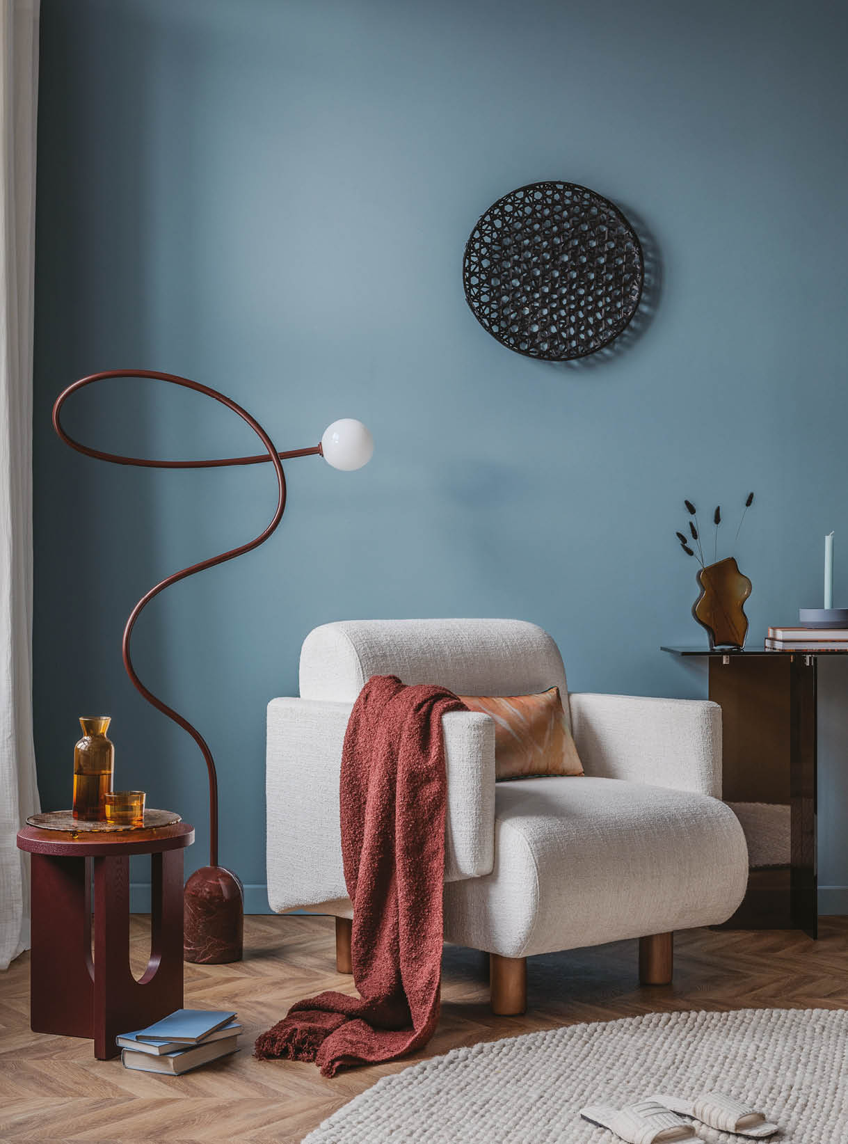 Modern sitting area featuring a soft white lounge chair, abstract wall decor, and deep-toned accent furniture.