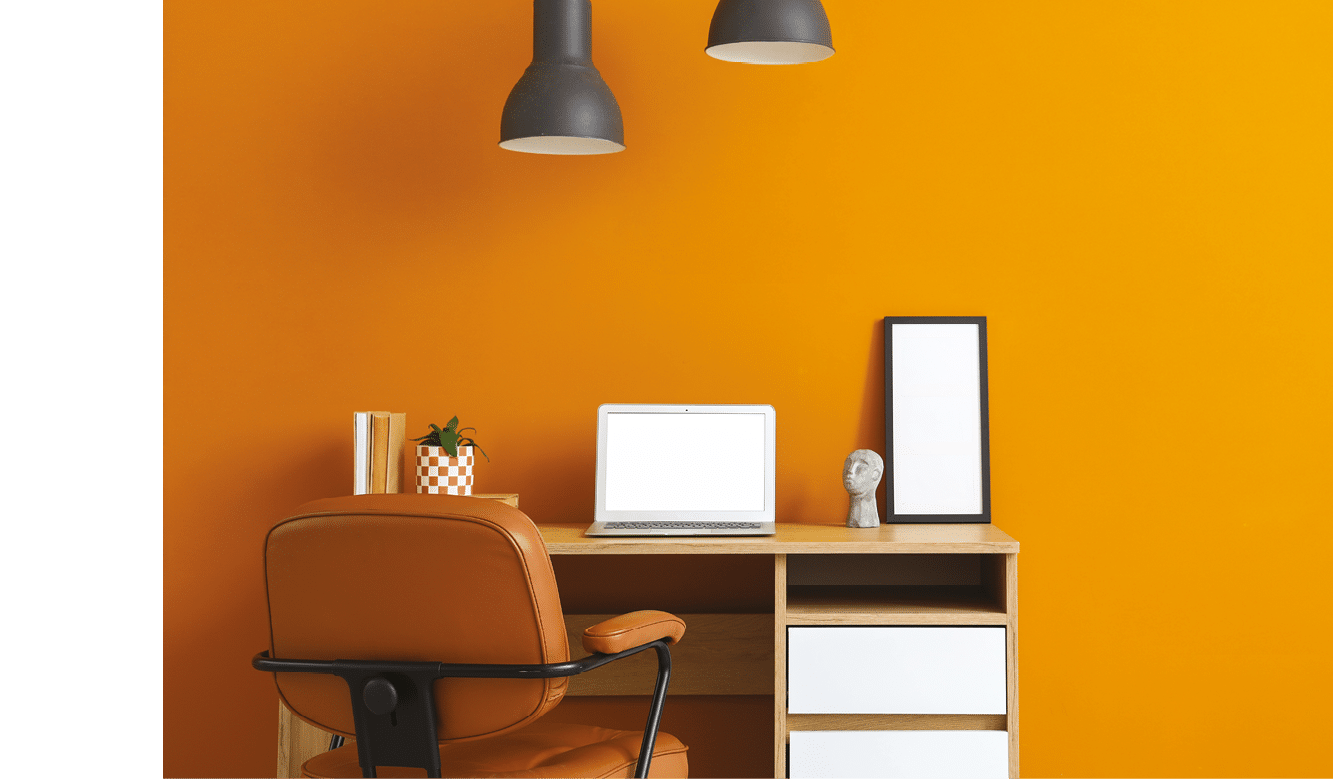 Workplace with blank laptop and lamps near orange wall