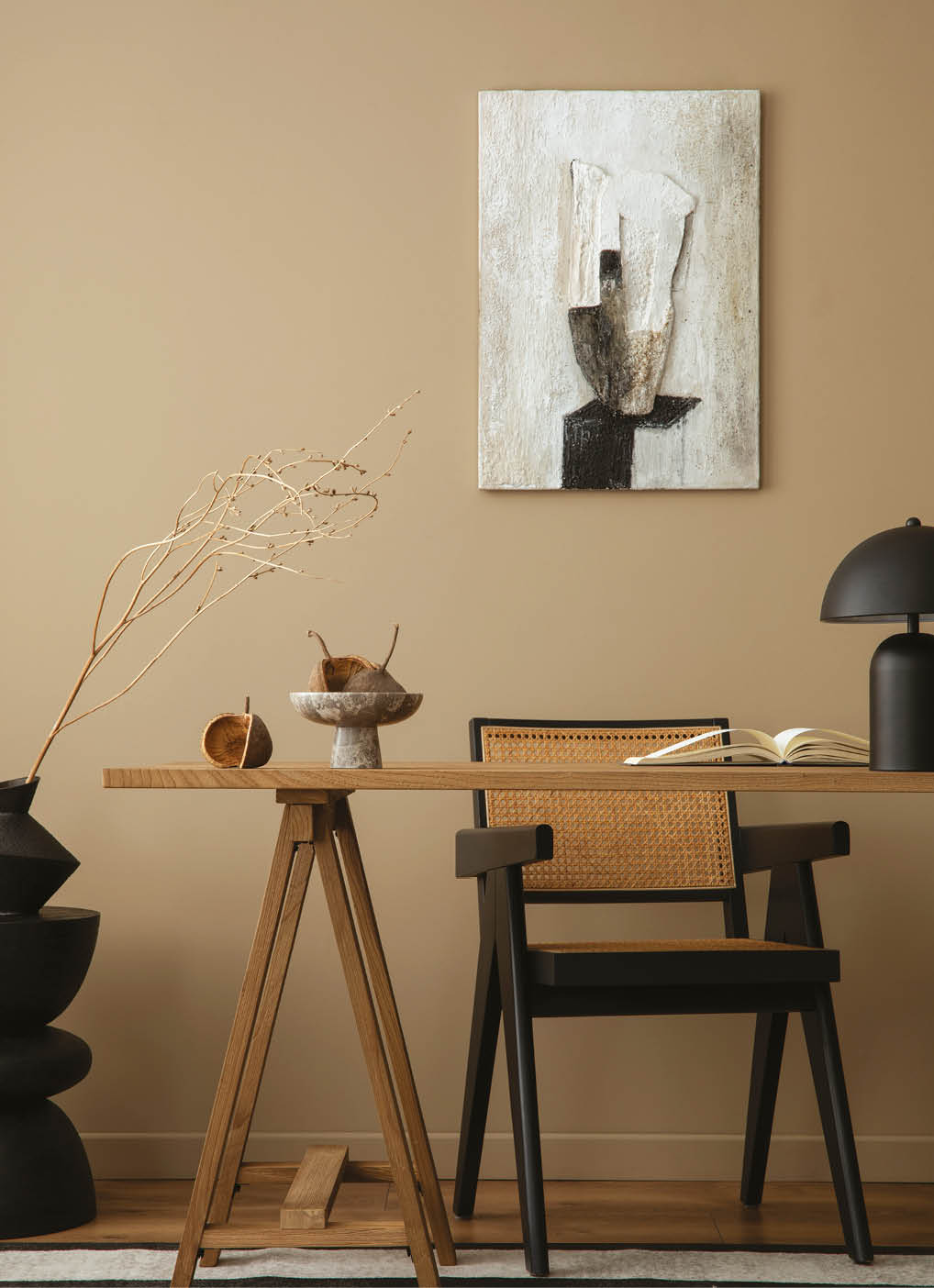 Cozy composition of workplace interior space with mock up poster frame, wooden desk, rattan chair, black lamp, books, patterned carpet, marble bowl and personal accessories. Home decor. Template.