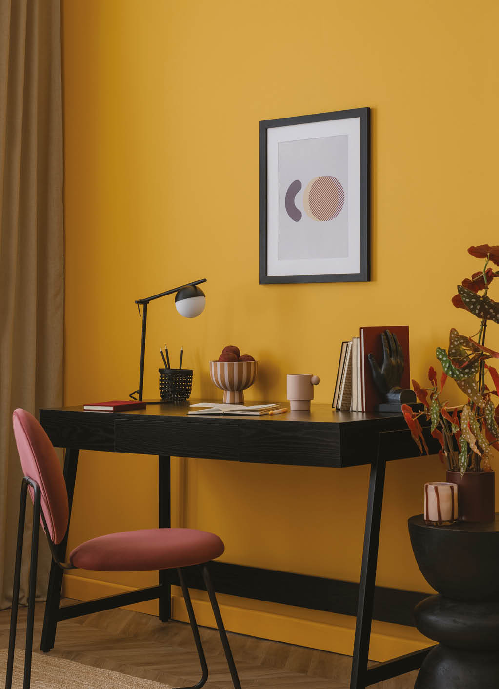 Warm living room interior with mock up poster frame, black desk, burgund chair, books, curtain, vase with flowers, simple lamp, yellow wall and personal accessories. Home decor. Template. 